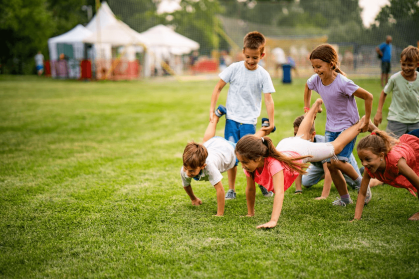 A group of children doing push ups on a grassy field.